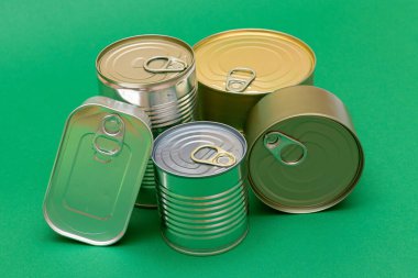 Yeşil Arkaplanda Boş Kenarlı İstiflenmiş Teneke Kutular Grubu. Konserve yiyecekler. Güvenli ve uzun vadeli yiyecek depolamak için farklı alüminyum kutular. Çelik Mühürlü Yiyecek Depolama Kutuları