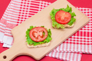 Domatesli pirinçli sandviç ve tahta kesim tahtasında marul. Kolay Kahvaltı 'da. Diyet yemek. Hızlı ve sağlıklı sandviçler. Lezzetli dolgulu kızarmış ekmek. Sağlıklı Beslenme Atıştırması