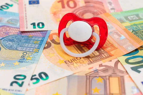 Childfree, Contraception and Birth Control Concept: Baby Pacifier on the Euro Banknotes. Having Children is Expensive and Unprofitable