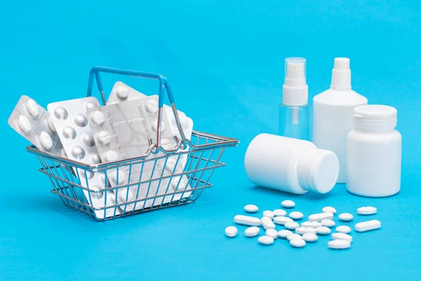 Buying Medicines. Expensive Medicine and Inflation Concept: Pills and Capsules in Shopping Basket on Blue Background. Global Pharmaceutical Industry and Big Pharma. Ordering Pharmaceutical Products