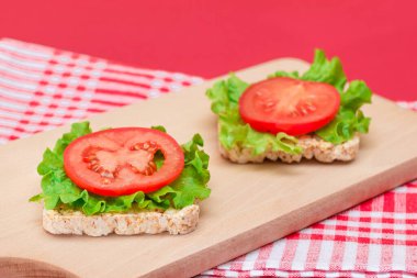 Domatesli pirinçli sandviç ve tahta kesim tahtasında marul. Kolay Kahvaltı 'da. Diyet yemek. Hızlı ve sağlıklı sandviçler. Lezzetli dolgulu kızarmış ekmek. Sağlıklı Beslenme Atıştırması