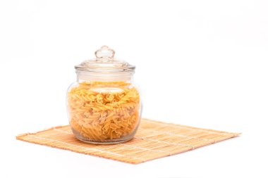 Beyaz Arkaplanda Cam Kavanozda Pişmemiş Fusilli Makarna. Çiğ ve kuru makarna. Sağlıksız ve şişman yiyecekler. İtalyan Kültürü