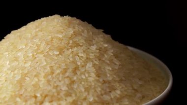 Dry Uncooked Parboiled Rice Heap Rotating against Black Background. A Pile of Raw Long Grain Rice. Asian Cuisine and Culture. Healthy Eating Ingredients. Diet Food