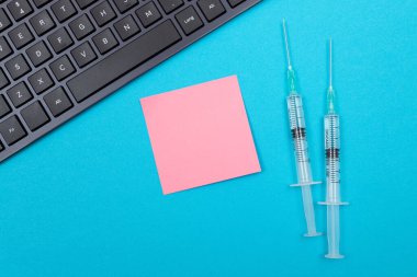 Aşılama, Bağışıklık Bilimi veya Yeniden Aşılama Konsepti - Bir Hastane veya Klinikte Mavi Masada Yatan İki Tıbbi Tek Kullanım Şırıngası. Boş Pembe Yapışkan Not - Uzayı Kopyala ile Moklonla