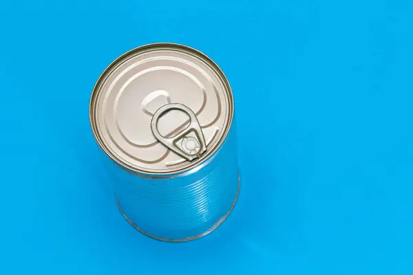 Unopened Tin Can with Blank Edge on Light Blue Background. Canned Food. Aluminum Can for Safe and Long Term Storage of Food. Steel Sealed Food Storage Container