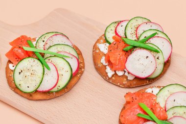 Taze somon, salatalık, turp, süzme peynir ve taze soğanlı çıtır krakerli sandviç. Kolay Kahvaltı 'da. Hızlı ve sağlıklı sandviçler. Lezzetli dolgulu kızarmış ekmek. Sağlıklı Beslenme Atıştırması