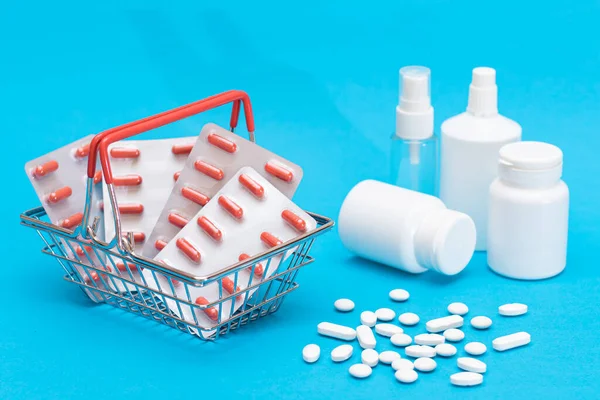 Buying Medicines. Expensive Medicine and Inflation Concept: Pills and Capsules in Shopping Basket on Blue Background. Global Pharmaceutical Industry and Big Pharma. Ordering Pharmaceutical Products