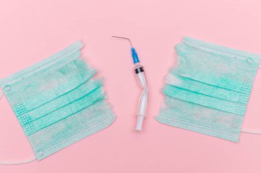 Aşı Karşıtı Hareket ve Maske Karşıtı Konsept - Kırık Tıbbi Şırınga ve Pembe Arkaplanda Yeşil Yırtık Tıbbi Maske. Salgın ve Kilitlenme Sonu - Üst Görünüm, Düz Yat