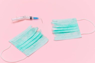 Aşı Karşıtı Hareket ve Maske Karşıtı Konsept - Kırık Tıbbi Şırınga ve Pembe Arkaplanda Yeşil Yırtık Tıbbi Maske. Salgın ve Kilitlenme Sonu - Üst Görünüm, Düz Yat