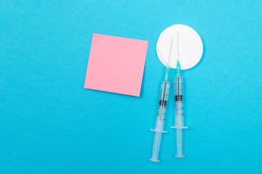Aşılama, Bağışıklık Bilimi veya Yeniden Aşılama Konsepti - Bir Hastane veya Klinikte Mavi Masada Yatan İki Tıbbi Tek Kullanım Şırıngası. Boş Pembe Yapışkan Not - Uzayı Kopyala ile Moklonla