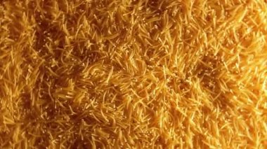 Saat Yönünde Dönen Pişmemiş Altın Eriştelerin Arkaplanı - Üst Görünüm. Kuru Vermicelli Dönüşü dokusu. Low Key Light ile Çiğ Makarna - Sağ Döndürme