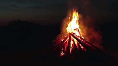 Big Burning Campfire at Summer Night against the Blue Sky. Wood on Fire. Flying Sparks. Travel and Tourism Concept. Giant Flaming Bonfire - Static Shot, Slow Motion