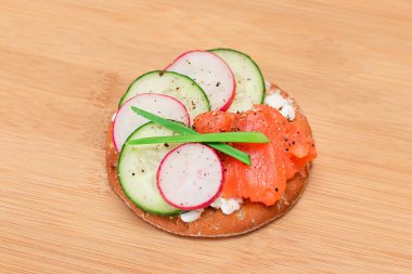 Crispy Cracker Sandwich with Salmon, Cucumber, Radish, Cottage Cheese and Green Onions on Bamboo Cutting Board. Easy Breakfast. Quick and Healthy Sandwiches. Crispbread with Tasty Filling