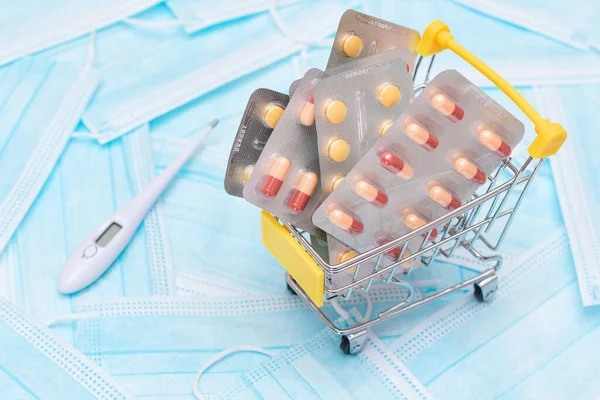Buying Medicines. Expensive Medicine and Inflation Concept: Pills and Capsules in Shopping Cart on the Surgical Masks. Global Pharmaceutical Industry and Big Pharma. Ordering Pharmaceutical Products