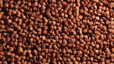 Kuru pişmemiş kahverengi karabuğday Groats, Yavaşça Saat Yönünün Tersine Dönen Üst Görünüm, Düşük Anahtar Işığı. Çiğ Büyük Karabuğday Taneleri. Rus, Ukrayna ve Beyaz Rusya Kültürü. Sola Döndür