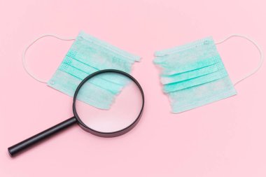 Anti Maske Hareketi - Yeşil Yırtık Tıbbi Maske Pembe Arkaplanda Büyüteç ile. Salgın ve Kilitlenme Sonu - Üst Görünüm, Düz Yat