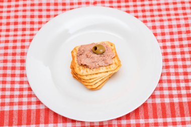 Crispy Salted Cracker with Liver Pate and Olives on White Plate. Easy Snack