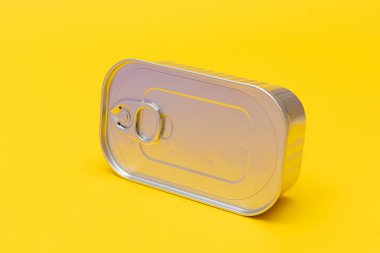 Sarı Arkaplan 'da boş kenarı olan işlenmemiş teneke kutu. Konserve yiyecekler. Güvenli ve uzun vadeli yiyecek depolama için alüminyum kutu. Çelik Mühürlü Yiyecek Depolama Kutusu