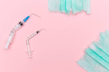 Aşı Karşıtı Hareket ve Maske Karşıtı Konsept - Kırık Tıbbi Şırınga ve Pembe Arkaplanda Yeşil Yırtık Tıbbi Maske. Salgın ve Kilitlenme Sonu - Üst Görünüm, Düz Yat