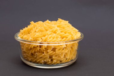 Kara Arkaplanda Cam Kavanoz 'da pişmemiş Fusilli Makarna. Şişman ve Sağlıksız Yemek. Klasik kuru sarmal makarna. İtalyan Kültür ve Mutfağı. Çiğ Makarna