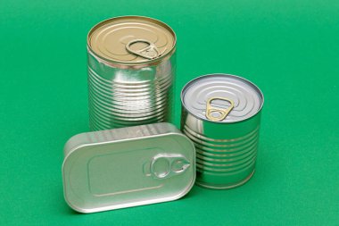 Yeşil Arkaplanda Boş Kenarlı İstiflenmiş Teneke Kutular Grubu. Konserve yiyecekler. Güvenli ve uzun vadeli yiyecek depolamak için farklı alüminyum kutular. Çelik Mühürlü Yiyecek Depolama Kutuları