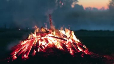 Büyük Kamp Ateşi, Sabah Erkenden veya Akşam Mavi Gök 'e Karşı Yanıyor. Ateşe odun. Uçan Kıvılcım. Seyahat ve Turizm Konsepti. Yaz 'da Devasa Şenlik Ateşi' nden Kalanlar - Statik Çekim, Zaman Aşımı
