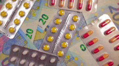 Enflasyon. Pahalı bir ilaç. Yüksek Sağlık Hizmetleri Maliyeti. Global İlaç Endüstrisi ve Tıbbi Ürünler. 20 Euro 'luk Banknotlarda Renkli Haplar ve Kapsüller - Üst Görünüm, Rotasyon Sağı