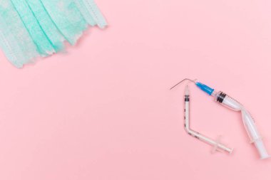 Aşı Karşıtı Hareket ve Maske Karşıtı Konsept - Kırık Tıbbi Şırınga ve Pembe Arkaplanda Yeşil Yırtık Tıbbi Maske. Salgın ve Kilitlenme Sonu - Üst Görünüm, Düz Yat