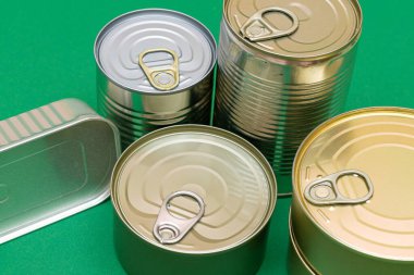 Yeşil Arkaplanda Boş Kenarlı İstiflenmiş Teneke Kutular Grubu. Konserve yiyecekler. Güvenli ve uzun vadeli yiyecek depolamak için farklı alüminyum kutular. Çelik Mühürlü Yiyecek Depolama Kutuları