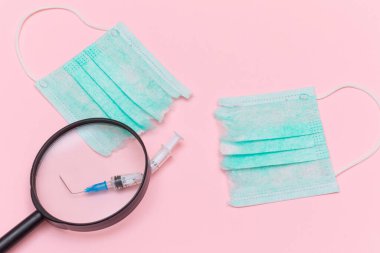 Aşı Karşıtı Hareket ve Maske Karşıtı Konsept - Kırık Tıbbi Şırınga ve Pembe Arkaplanda Büyüteç Camlı Yeşil Yırtık Tıbbi Maske. Salgın ve Kilitlenme Sonu - Üst Görünüm, Düz Yat