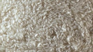 Dry Uncooked White Rice Background Rotating Right - Top View, Low Key Light. Scattered Raw Long Grain Rice. Asian Cuisine and Culture. Healthy Eating Ingredients. Diet Food