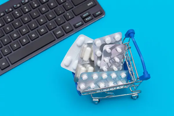 İlaç siparişi veriyorum. Pahalı İlaç ve Enflasyon Konsepti: Mavi Arkaplanda bir alışveriş arabasında haplar ve kapsüller. Global İlaç Endüstrisi ve Büyük İlaç. İlaç Ticareti