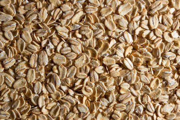 Uncooked Oat Flakes background - Top View, Flat Lay. Scattered Dry and Raw Oat Flakes. Healthy Breakfast and Diet Eating Ingredients