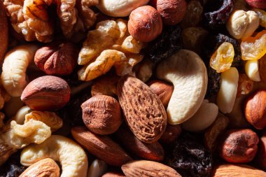 Karışık fındık, badem, ceviz, kaju, fıstık, fındık, kuru erik ve kuru üzüm. Farklı fındık karışımı. Çeşitli Fındık ve Kurutulmuş Meyvelerin Arkaplanı