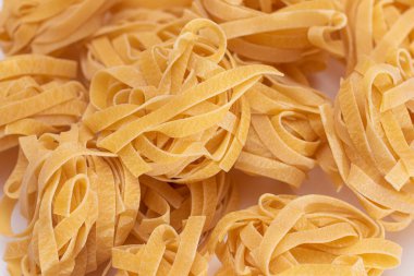 Klasik İtalyan Çiğ Yumurta Fettuccine Beyaz Masa 'da. Kuru, bükülmemiş, pişmemiş makarna. İtalyan Kültür ve Mutfağı. Çiğ Altın Makarna Deseni