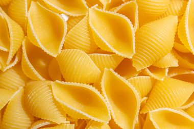 Pişmemiş Conchiglie Pasta: Konchiglie Macaroni 'nin Mutfak Tuvali, Gurme Yemekleri İçin Canlı ve Dokulu Bir Arkaplan Oluşturuyor. Kuru makarna. Raw Macaroni - Top View, Düz Yat