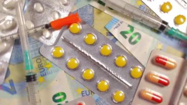 Enflasyon. Pahalı bir ilaç. Yüksek Sağlık Hizmetleri Maliyeti. Global İlaç Endüstrisi ve Tıbbi Ürünler. Yirmi Avro Banknotları Üzerinde Farklı İlaç ve Şırıngalar - En İyi Görünüm, Rotasyon Sağı
