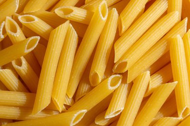 Pişmemiş Penne Rigate Makarnası: Gurme Aşçılık İçin Canlı ve Dokulu Bir Arkaplan Oluşturan Penne Makarna Mutfağı. Kuru makarna. Raw Macaroni - Top View, Düz Yat