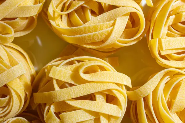 Pişmemiş Yumurta Bazlı Fettuccine Pasta: Kurdele şekilli Makarna Mutfağı, Gurme Aşçılığı İçin Canlı ve Dokulu Bir Arkaplan Oluşturuyor. Kuru makarna. Raw Macaroni - Top View, Düz Yat