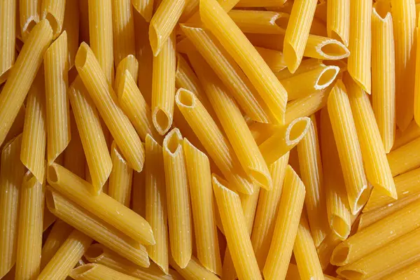 Pişmemiş Penne Rigate Makarnası: Gurme Aşçılık İçin Canlı ve Dokulu Bir Arkaplan Oluşturan Penne Makarna Mutfağı. Kuru makarna. Raw Macaroni - Top View, Düz Yat