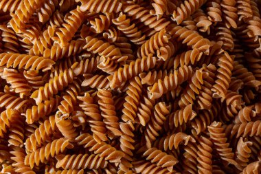 Pişmemiş Whole Grain Fusilli Makarna: Gurme Aşçılık İçin Canlı ve Dokulu Bir Arkaplan Oluşturan Tam Buğday Büfesi. Tam Tahıllı Kurutulmuş Makarna. Tam buğday hamurlu makarna.