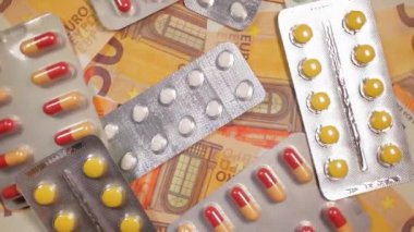 Enflasyon. Pahalı bir ilaç. Yüksek Sağlık Hizmetleri Maliyeti. Global İlaç Endüstrisi ve Tıbbi Ürünler. 50 Euro 'luk Banknotlardaki Haplar - Üst Görünüm, Yavaş Dönüşüm