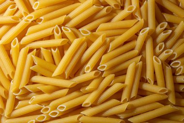 Pişmemiş Penne Rigate Makarnası: Gurme Aşçılık İçin Canlı ve Dokulu Bir Arkaplan Oluşturan Penne Makarna Mutfağı. Kuru makarna. Raw Macaroni - Top View, Düz Yat