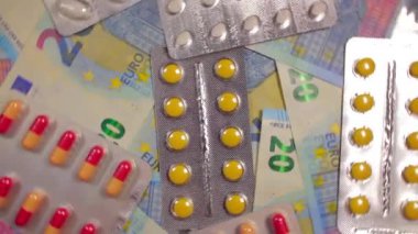 Enflasyon. Pahalı bir ilaç. Yüksek Sağlık Hizmetleri Maliyeti. Global İlaç Endüstrisi ve Tıbbi Ürünler. 20 Euro 'luk Banknotlarda Renkli Haplar ve Kapsüller - Üst Görünüm, Dönüşüm Solu