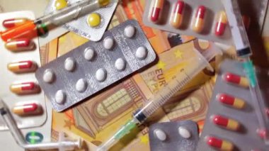 Enflasyon. Pahalı bir ilaç. Yüksek Sağlık Hizmetleri Maliyeti. Global İlaç Endüstrisi ve Tıbbi Ürünler. Elli Avro Banknotunda Farklı İlaç ve Şırıngalar - Üst Görünüm, Dönüşüm Solu