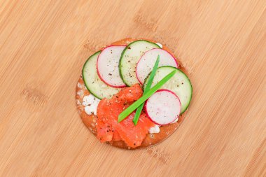 Crispy Cracker Sandwich with Salmon, Cucumber, Radish, Cottage Cheese and Green Onions on Bamboo Cutting Board. Easy Breakfast. Quick and Healthy Sandwiches. Crispbread with Tasty Filling