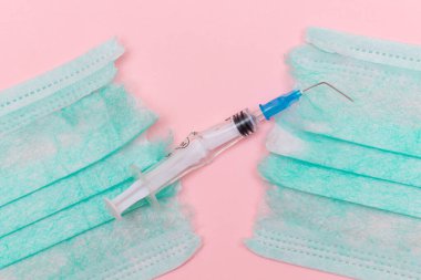 Aşı Karşıtı Hareket ve Maske Karşıtı Konsept - Kırık Tıbbi Şırınga ve Pembe Arkaplanda Yeşil Yırtık Tıbbi Maske. Salgın ve Kilitlenme Sonu - Üst Görünüm, Düz Yat