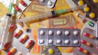 Enflasyon. Pahalı bir ilaç. Yüksek Sağlık Hizmetleri Maliyeti. Global İlaç Endüstrisi ve Tıbbi Ürünler. Elli Avro Banknotunda Farklı İlaç ve Şırıngalar - Üst Görünüm, Dönüşüm Hakkı