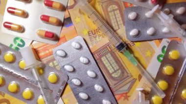 Enflasyon. Pahalı bir ilaç. Yüksek Sağlık Hizmetleri Maliyeti. Global İlaç Endüstrisi ve Tıbbi Ürünler. Elli Avro Banknotunda Farklı Haplar ve Şırıngalar - Üst Görünüm, Yavaş Dönüşüm