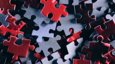 Saat Yönünün Tersine Yavaşça Dönen Renkli Bulmaca Parçalarının Arkaplanı - Üst Görünüm, Yakın Çekim. Tamamlanmamış Kırmızı ve Gri Yapbozun Yapbozu Düşük Anahtar Işıklı - Sol Döndürme